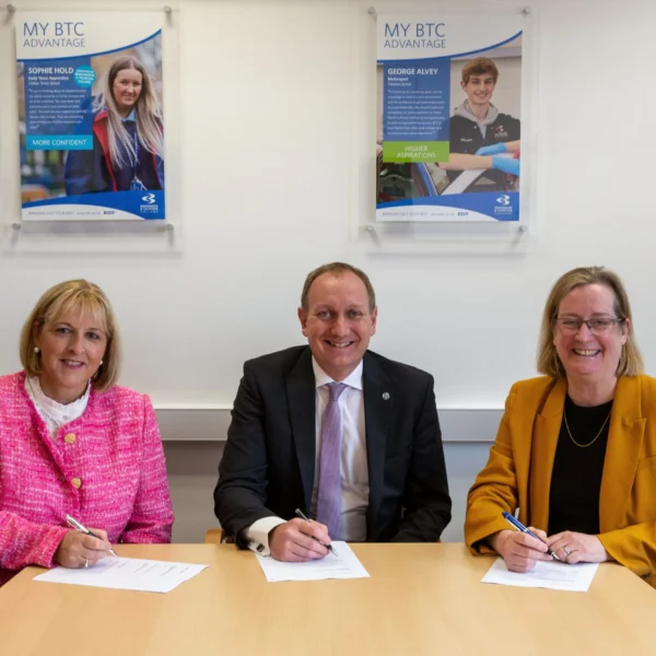 Three people sitting at a table signing documents