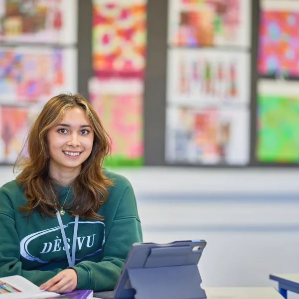 A young girl sitting at a desk with an iPad.