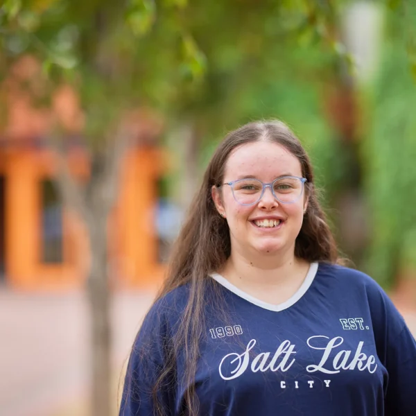A young woman wearing a navy blue t-shirt with 'Salt Lake City' written on it.