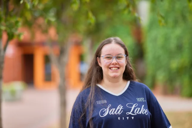 A young woman wearing a navy blue t-shirt with 'Salt Lake City' written on it.