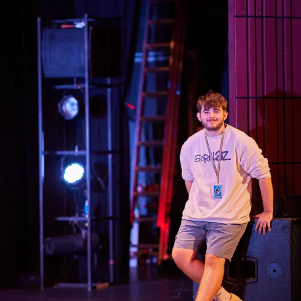 A man standing on a stage with a lanyard around his neck.