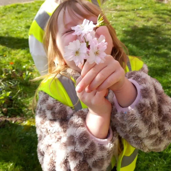 A young girl holding white flowers up to her face.