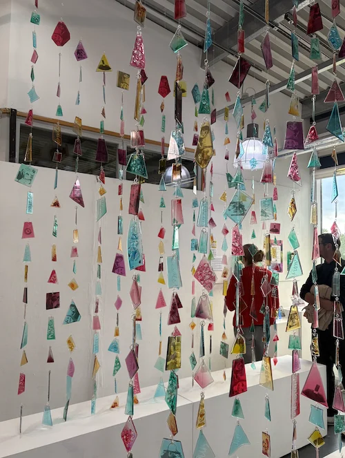 An art installation with colorful paper shapes hanging from the ceiling.