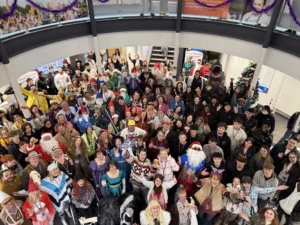 Large group of people gathered indoors, many wearing costumes.