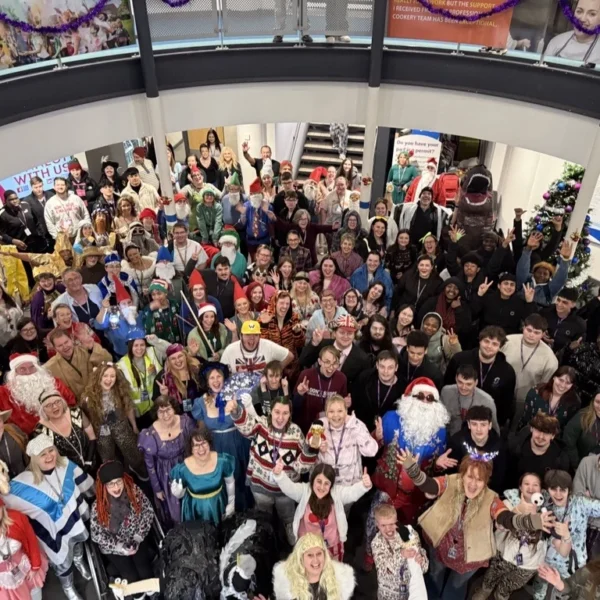 Large group of people gathered indoors, many wearing costumes.