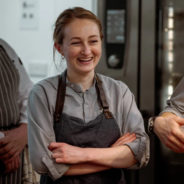 Woman in a kitchen with arms crossed smiling