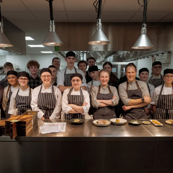 A group of chefs and kitchen staff standing behind a counter.