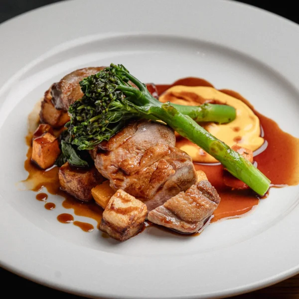 a plate of food with meat and vegetables on a wooden table