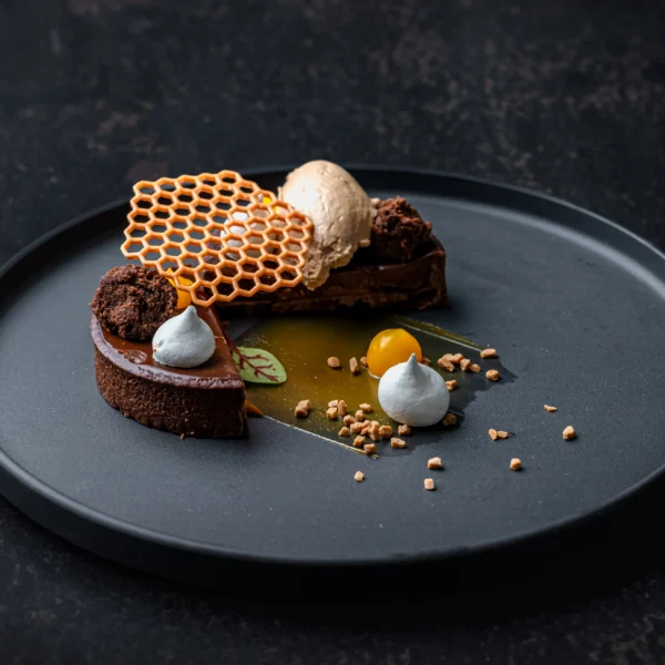 A dessert plate with chocolate cake, honeycomb, and creamy toppings.