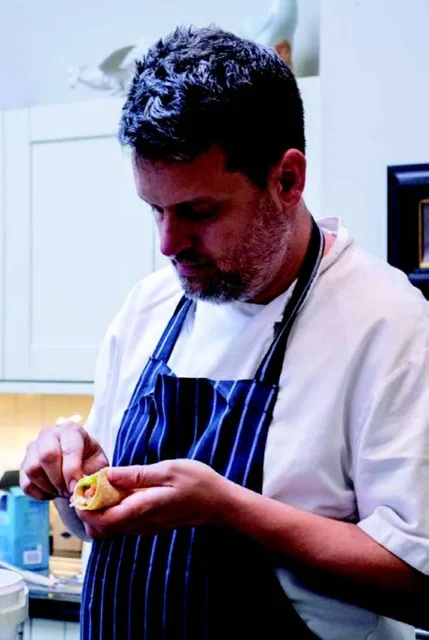 a man in a kitchen peeling a piece of fruit.