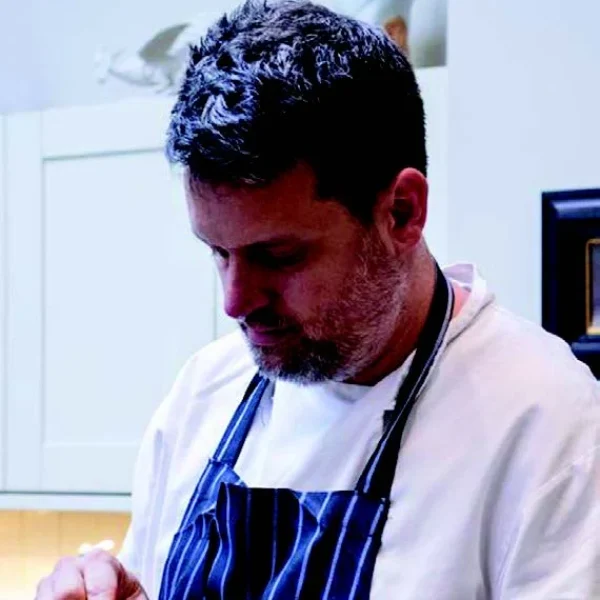 a man in a kitchen peeling a piece of fruit.