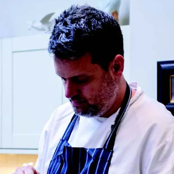 a man in a kitchen peeling a piece of fruit.