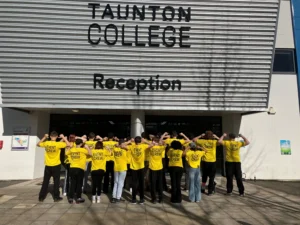A group of people wearing yellow t-shirts standing outside Taunton College reception.