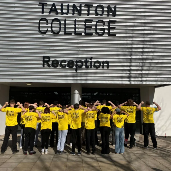 A group of people wearing yellow t-shirts standing outside Taunton College reception.