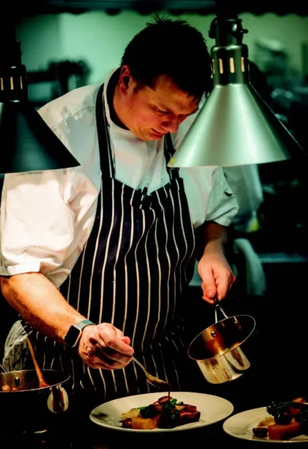 Chef plating a dish in a kitchen.