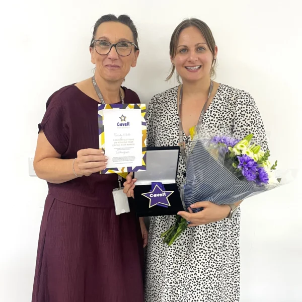 UCS Deputy Head of Nursing and Health Professions, Maria Santrian, presenting Emily White with her Cavell Star Award and a bouquet of flowers. Both are smiling at the camera.